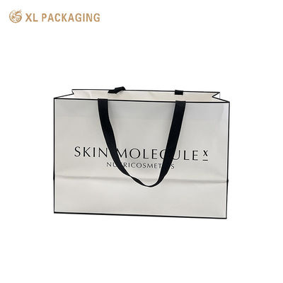 Bolsa de regalo de papel de arte de marca de lujo de color blanco mate con mango de cinta de tejido negro ancho para venta al por menor de cosméticos