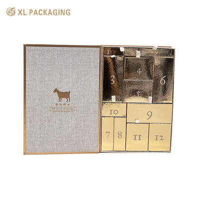 Caja de regalo de calendario de cuenta regresiva con forma de libro al por mayor, caja abatible magnética con 12 cajones dorados, lengüeta de extracción de cinta para cosméticos de cuidado de la piel