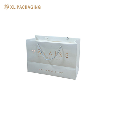 Bolsas de papel de arte blanco duro con logotipo personalizado Embalaje de compras de lujo con asas troqueladas Revestimiento resistente a los arañazos Diseño fácil de transportar Duradero para regalos pesados Elegante para experiencias de marca