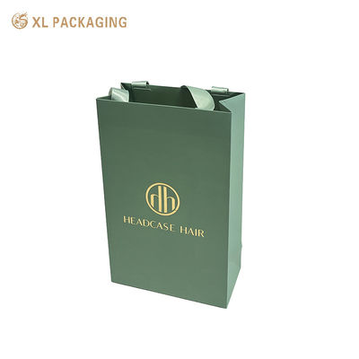 Bolsa de regalo de papel artístico esmerilado verde salvia mate con logotipo personalizado de lámina dorada y asas anchas de cinta satinada del mismo color