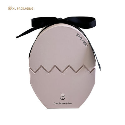 Cajas de regalo de papel de chocolate en forma de huevo rosa de lujo con cinta. Envase elegante de Pascua.